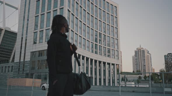 Outdoor Portrait of Sporty African American Man with Sport Bag Standing Near Stadium Building and