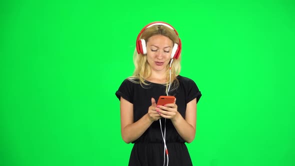 Girl Walks in Big Red Headphones and with a Smartphone, Switches Music and Dancing. Chroma Key. Slow