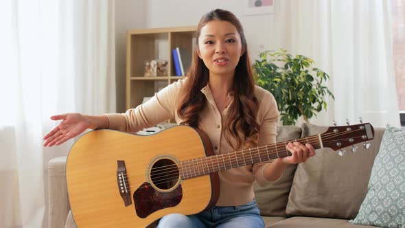 Young Woman with Guitar Videoblogging at Home