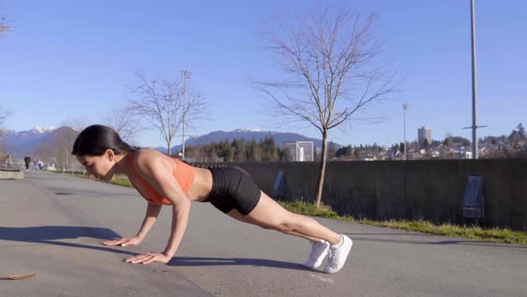 Focused young woman doing pushups on curb in bodyweight training