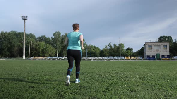 Senior woman running on the green field