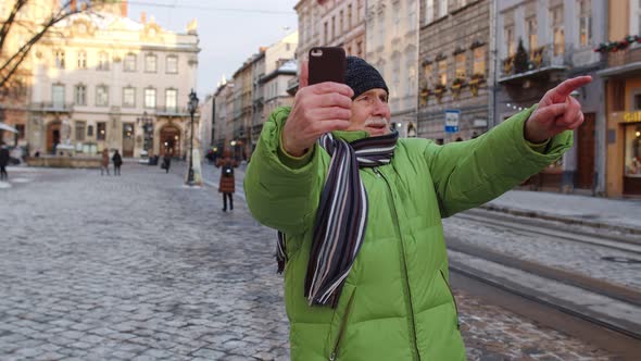 Senior Man Tourist Taking Selfie Making Online Video Call with Smart Phone in Winter City Center