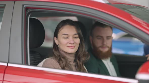 Young Brunette Caucasian Woman with Brown Eyes Closing Car Door and Talking To Blurred Man Sitting