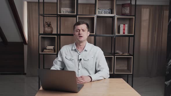 Man Gives an Interview Sitting at a Table with a Laptop