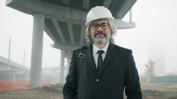 Portrait of Successful Architect Standing Outside in Construction Site Wearing Safety Helmet