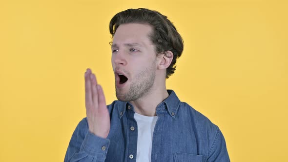 Portrait of Tired Young Man Yawning on Yellow Background