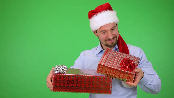 A Man in Christmas Hat Holds Presents and He Is Happy with Them and Smiles To Camera - Green Screen