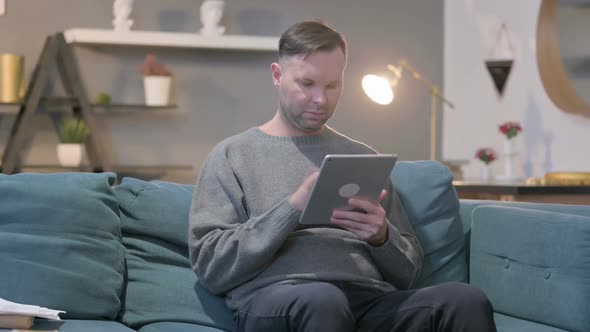 Casual Man Using Tablet While Sitting on Sofa