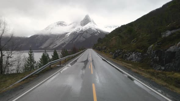 Wet Arctic road in direction of snow-covered Stetind mountain, Tysfjord, Norway