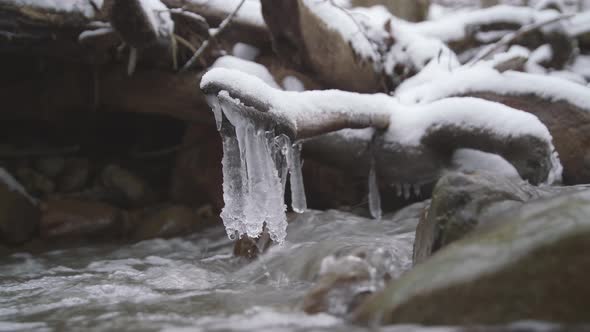 Ice Hanging on a Stick Above Flowing Stream of Water