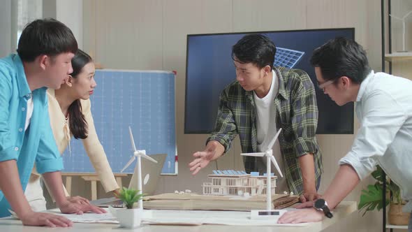 Asian Engineers Group Having A Meeting About The Model Of A Small House With Solar Panel