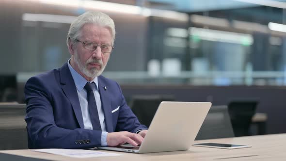 Old Businessman with Laptop Smiling at Camera