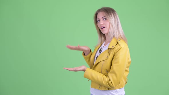 Happy Young Rebellious Blonde Woman Making Mistake While Showing Something