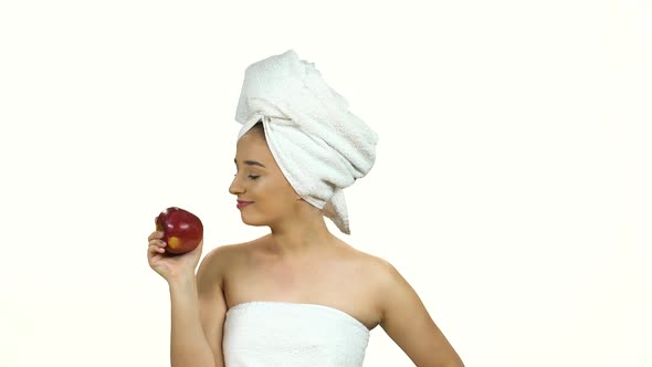 Girl in White Towel on Her Head Eats a Red Apple with Pleasure Isolated on White Background