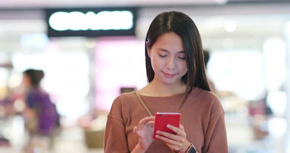 Woman check on the discount in mobile phone inside shopping plaza