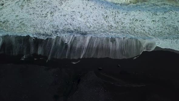 Top down drone aerial of waves coming up onto the black sand beach near Vik in Iceland