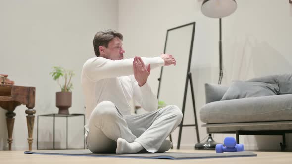 Middle Aged Man Doing Stretches on Yoga Mat at Home