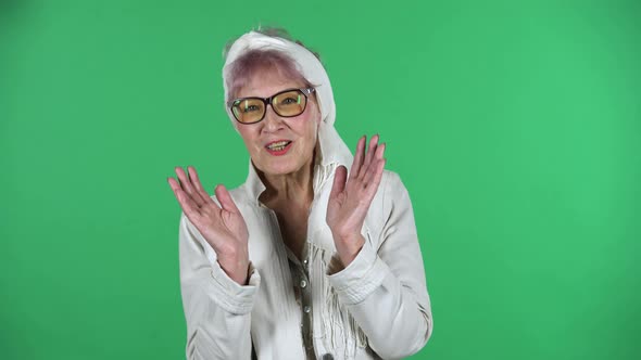 Portrait of Old Stylish Woman Is Looking Straight and Smiling Isolated Over Green Background.