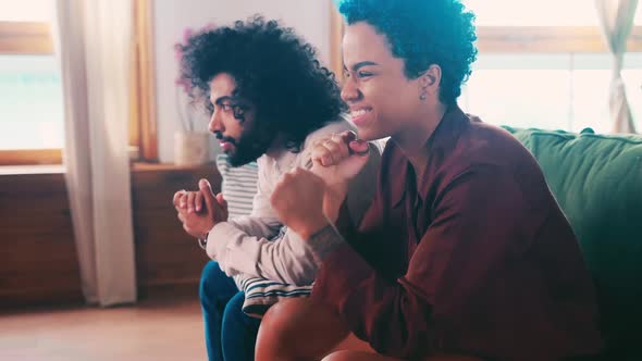 Young Arabian Man and African American Woman Cheer for Favorite Football Team