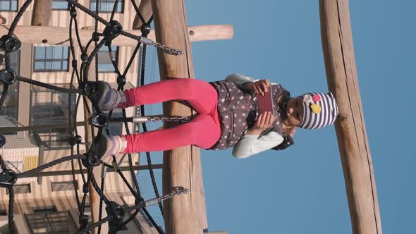 Little Girl Sitting with Smartphone on Playground