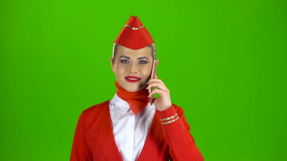 Stewardess Speaks on the Phone and Paces Into the Distance. Green Screen.