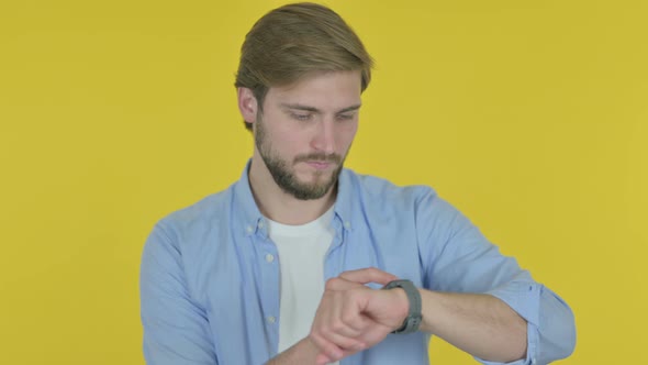 Young Man Using Smartwatch on Yellow Background