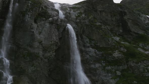 Aerial View Close Up Flight with Mountain Waterfalls Flowing From Glacier Over Rocks