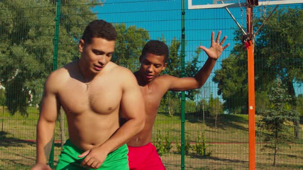 Two Shirtless Friends Playing Basketball on Court