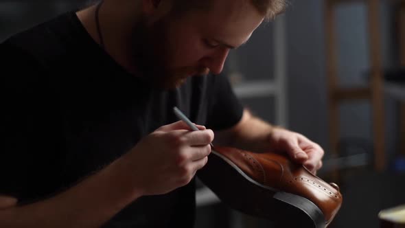 Closeup Portrait of Shoemaker Painting Heel and Sole of Light Brown Leather Shoes with Brush