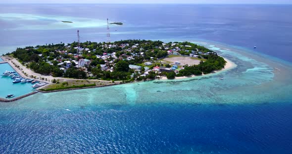 Beautiful flying tourism shot of a white sandy paradise beach and blue water background in 4K