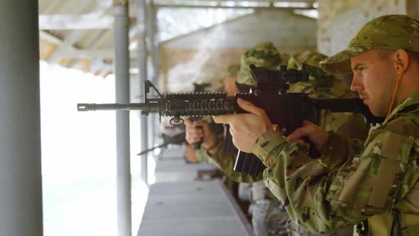 Side view of mixed-race military soldiers shooting rifle in target practice during training 4k