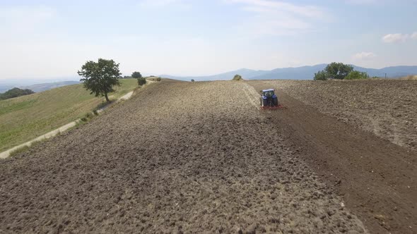 Farmer on tractor plowing a field in Umbria, Italy