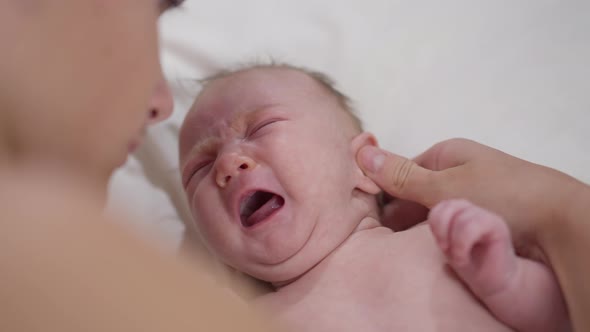 Closeup Portrait Crying Newborn Infant with Teenage Boy Stroking Ear Talking Hugging Child