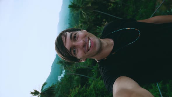 Vertical Video Portrait of Smiling Young Man Tourist Making a Selfie Video on Green Jungle Forest