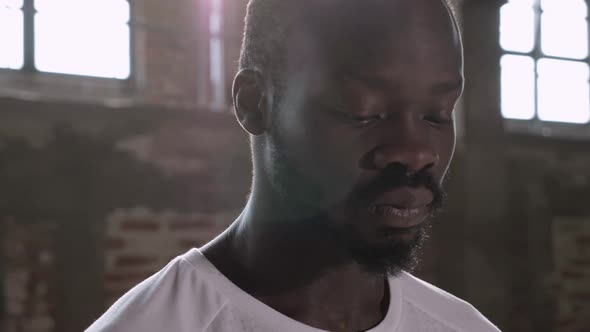 Portrait of black man in white t-shirt looking at camera indoors