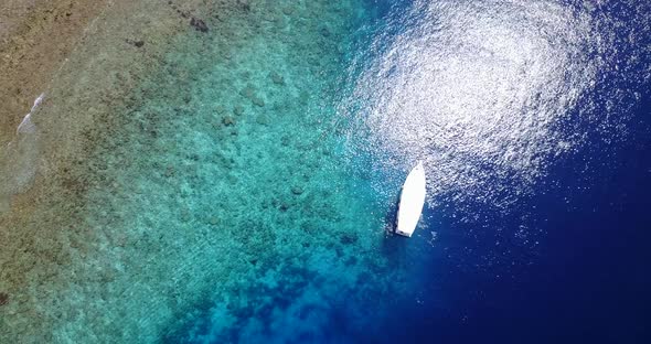 Tropical flying tourism shot of a white sand paradise beach and blue sea background in vibrant 4K