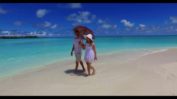 Romantic couple sunbathe on tropical seashore beach wildlife by blue water and white sandy backgroun