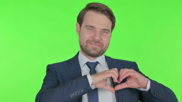 Young Businessman showing Heart Shape by Hands on Green Background