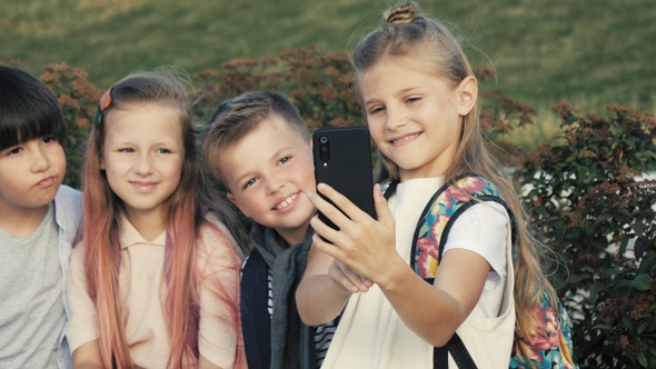 Four children are sitting on a bench and trying to make selfie