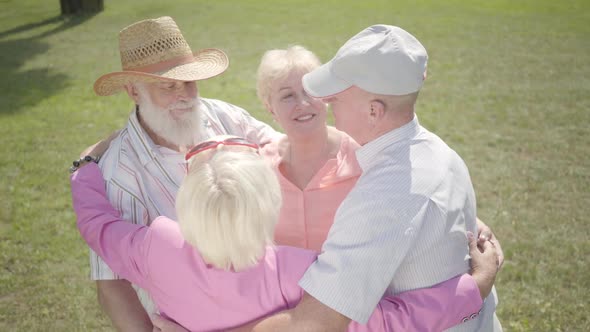 Two Cute Mature Couples Hugging in the Park Together Standing in Circle