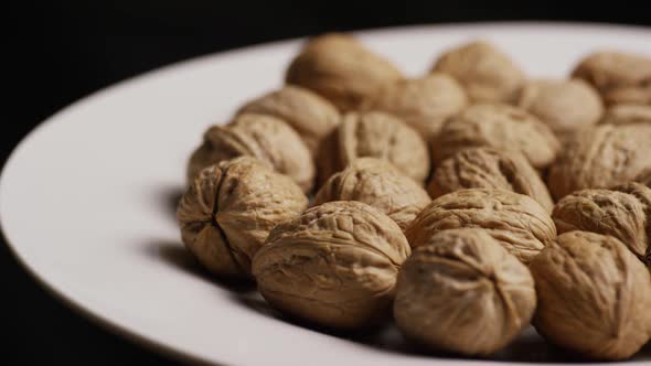 Cinematic, rotating shot of walnuts in their shells on a white surface - WALNUTS 