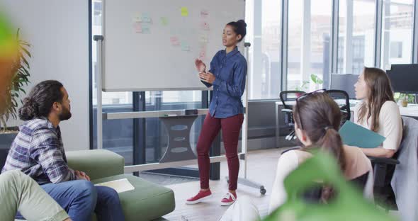 Diverse group of business colleagues brainstorming using whiteboard in meeting room