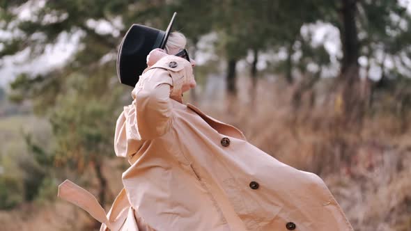 Portrait of Young Stylish Woman in Coat Dancing in Forest