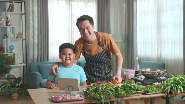 Asian Man Father And Little Child Son Looking And Smile To Camera While Cooking Together At Home