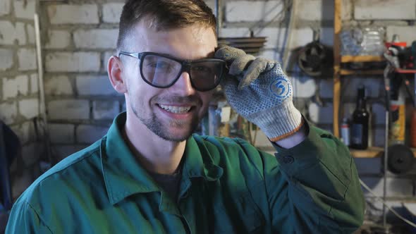 Happy Young Mechanic Taking Off Protective Eyewear After Finishing His Job