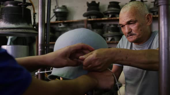 Mixed race man working at a hat factory