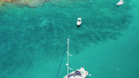 Yacht with Lowered Sheets and Caters in Azure Sea Near Coast