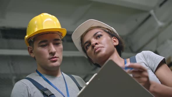 Factory Workers Talking and Writing down on Clipboard