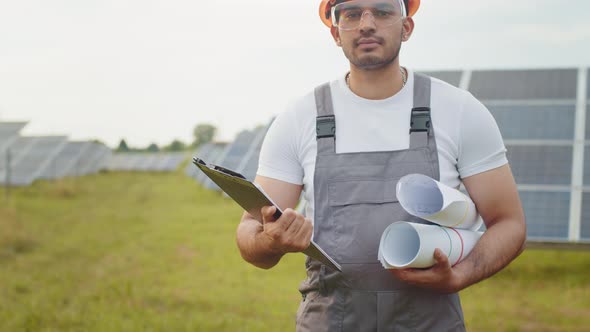 Close Up of Competent Engineer in Uniform Standing Outdoors Among Solar Panels