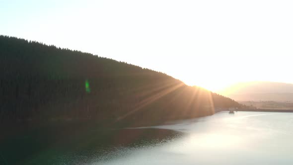 Aerial shot, Frumoasa Dam Romania with bright sunset and lens flare
